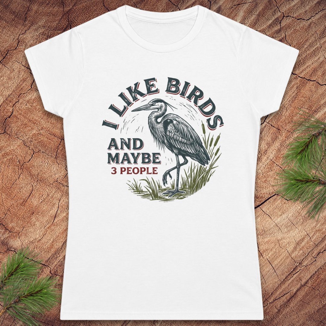 White t-shirt with a heron bird and text on a wood background.