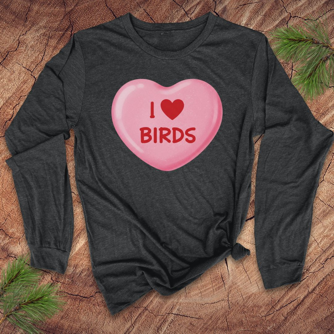 Dark long-sleeve shirt with a pink heart-shaped candy design and 'I ❤️ BIRDS' text on a wooden surface.