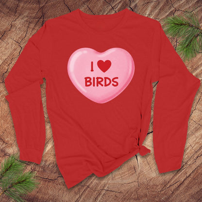 Red long-sleeve shirt with a pink heart-shaped candy design on a wooden surface.