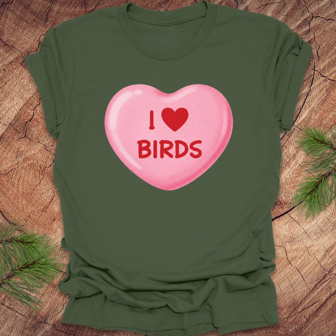 Green t-shirt with a pink heart-shaped candy design with text, 'i heart birds' on a wooden surface