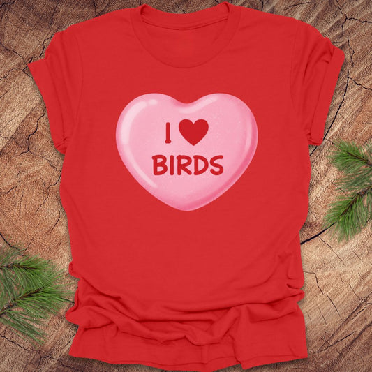 Red t-shirt with a pink candy heart graphic and 'I ❤️ BIRDS' text on a wooden surface.