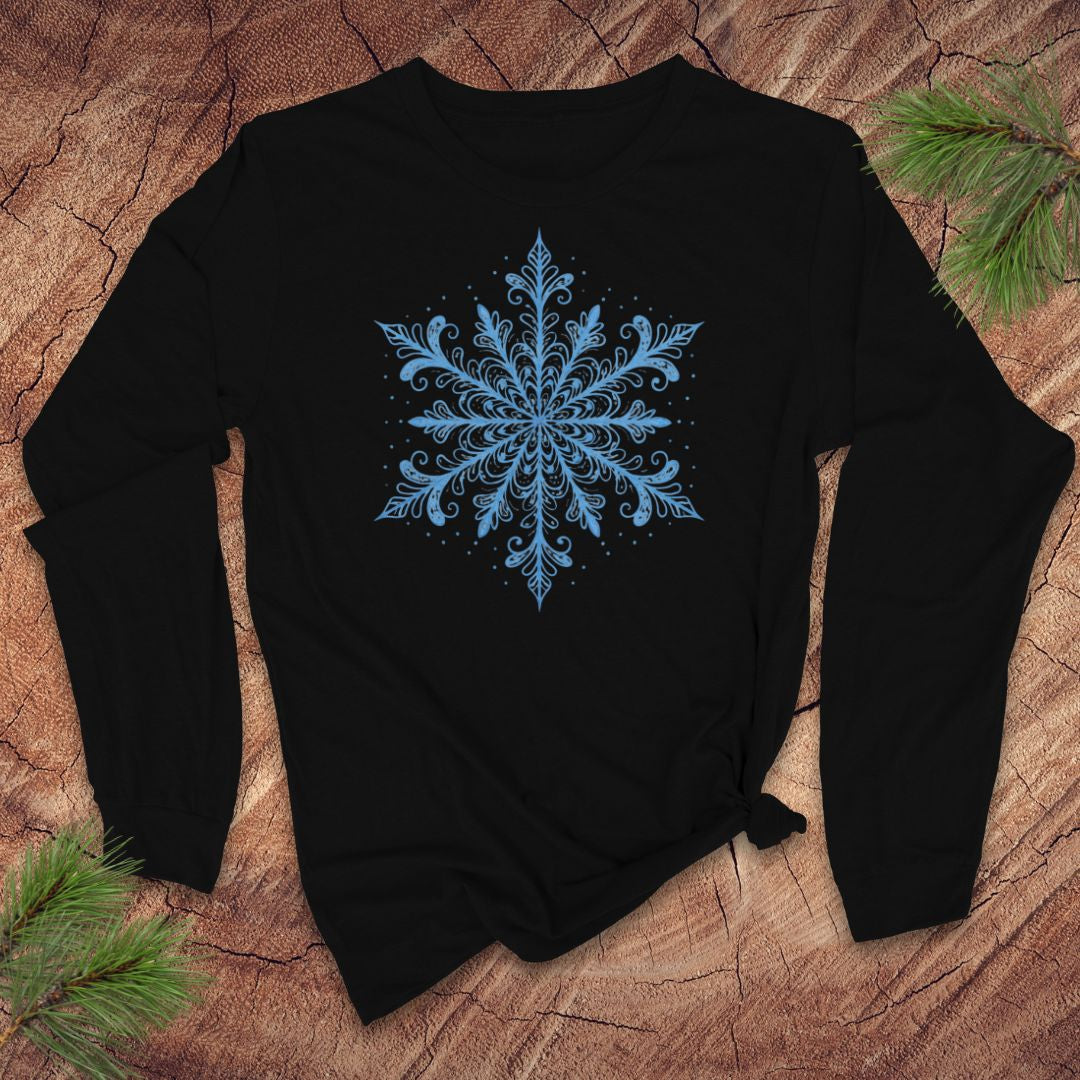 Black long-sleeve shirt with an icy blue snowflake design on a wooden surface with pine branches.