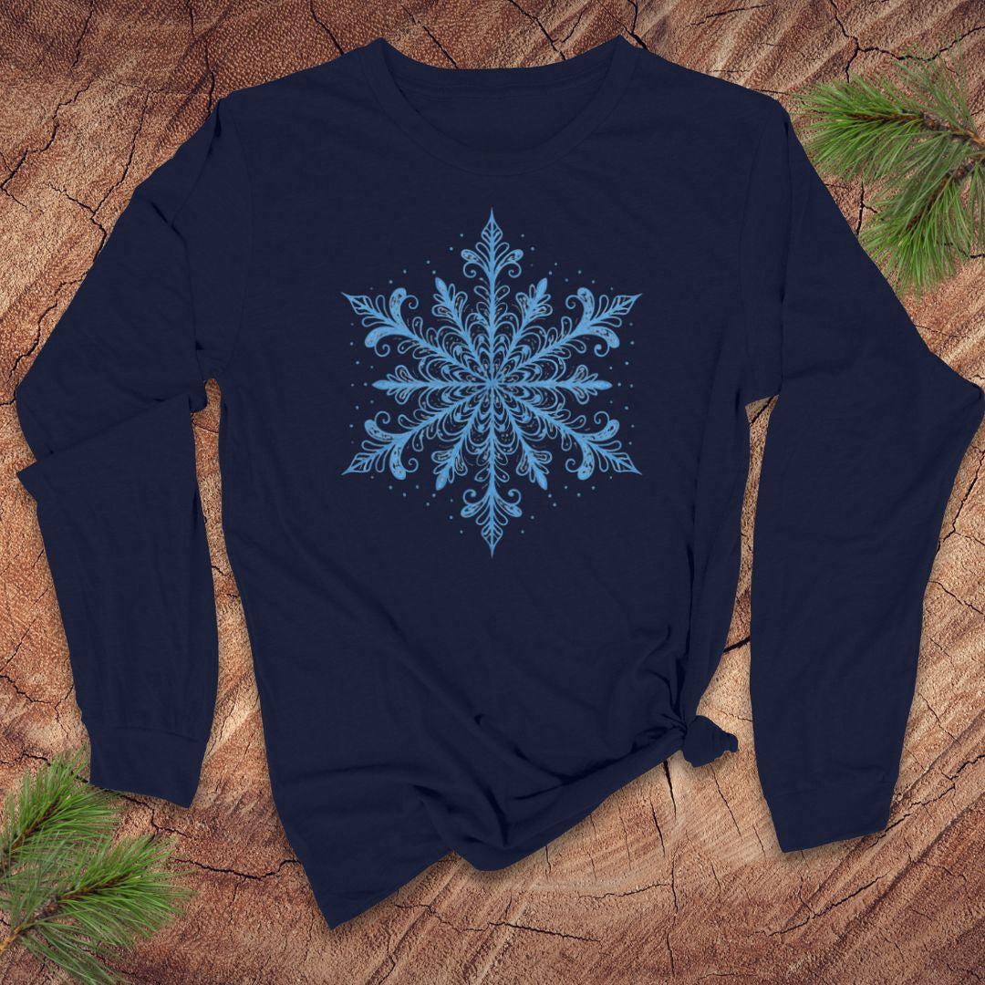 Navy blue long-sleeve shirt with an icy blue snowflake design on a wooden surface with pine branches.