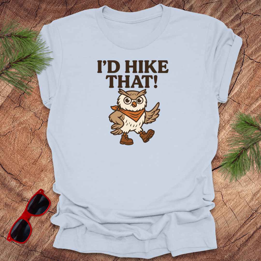 A light blue t-shirt with a graphic of an owl wearing a hat and the text 'I'D HIKE THAT!' printed above.