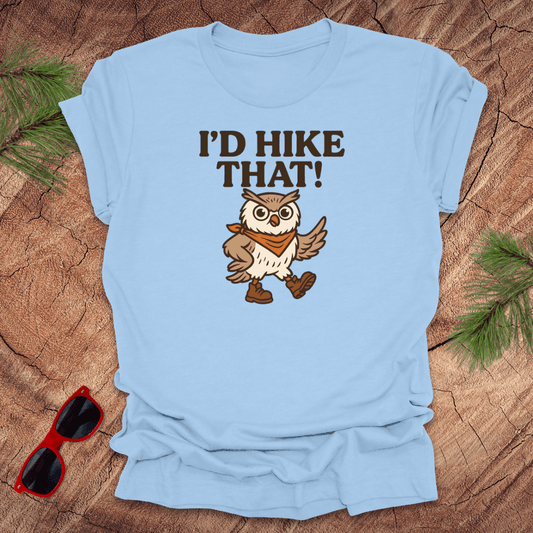 A baby blue t-shirt with a graphic of an owl wearing a hat and the text 'I'D HIKE THAT!' printed above.