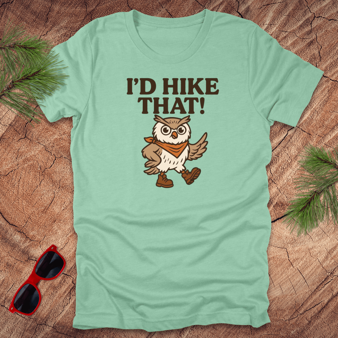 A mint green t-shirt with a graphic of an owl wearing a hat and the text 'I'D HIKE THAT!' printed above.