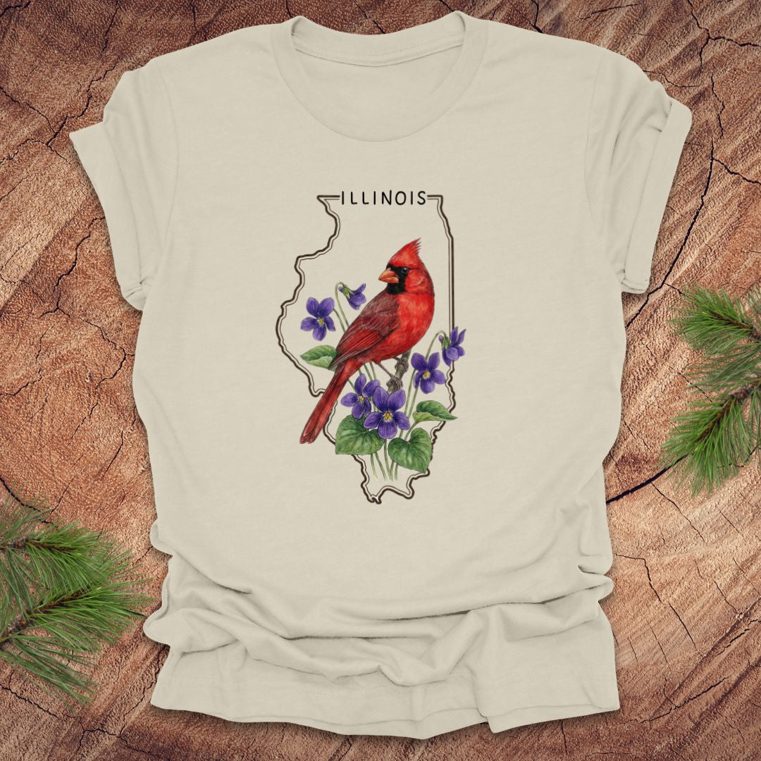 Beige t-shirt with Illinois state outline and state bird and flower cardinal and violets design on a wooden surface