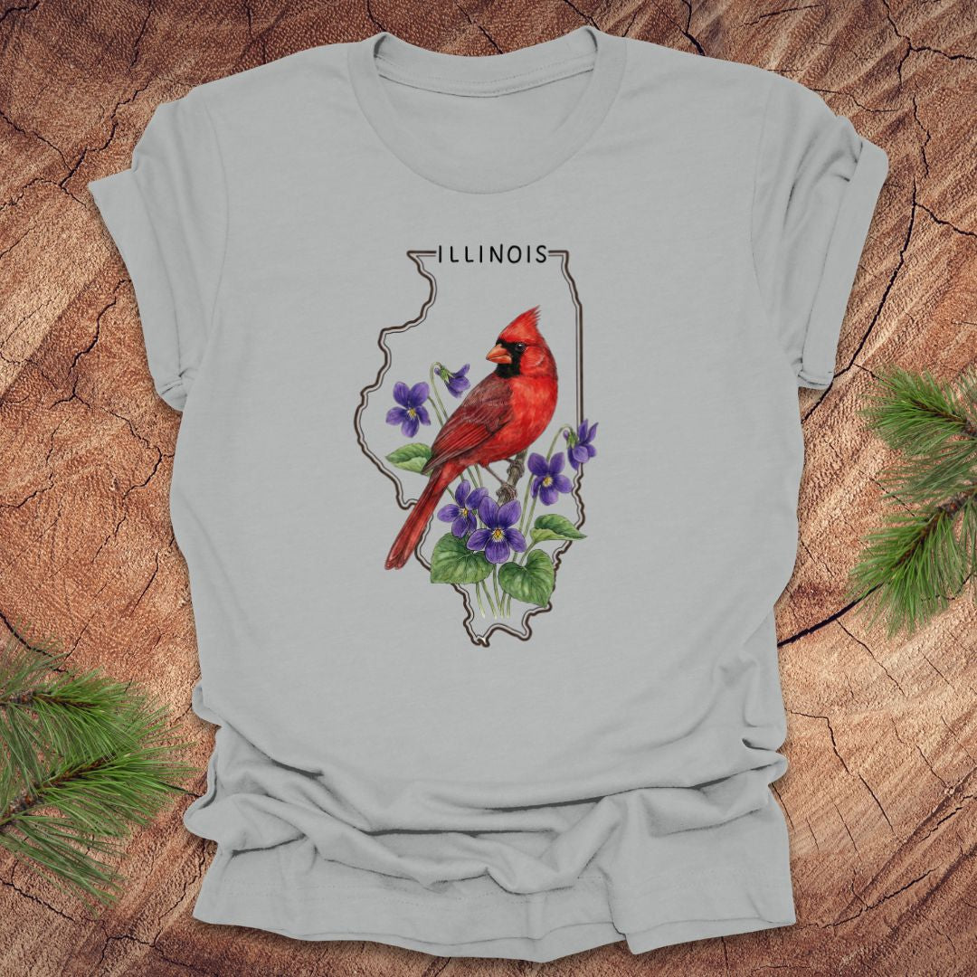 Silver t-shirt with Illinois state outline and state bird and flower cardinal and violets design on a wooden surface