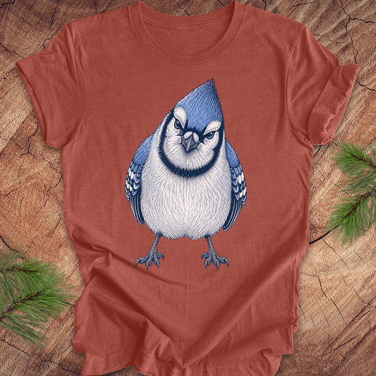 Red t-shirt with a blue jay bird design on a wooden surface.