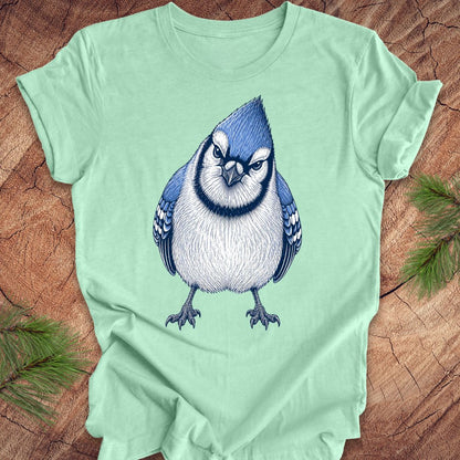 Mint green t-shirt with a blue jay bird design on a wooden surface.