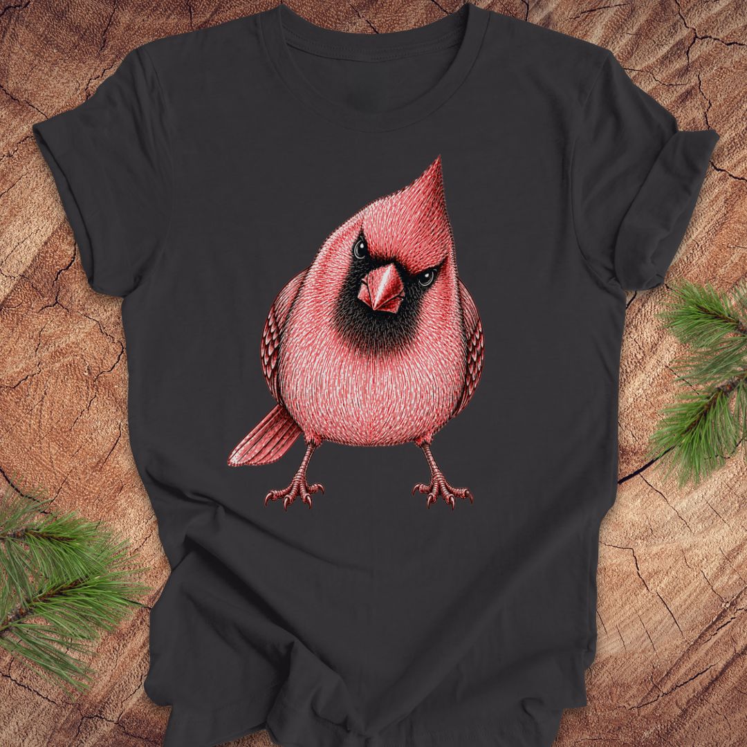 Dark gray t-shirt with a red cardinal bird design on a wooden surface with pine branches.