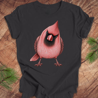 Dark gray t-shirt with a red cardinal bird design on a wooden surface with pine branches.