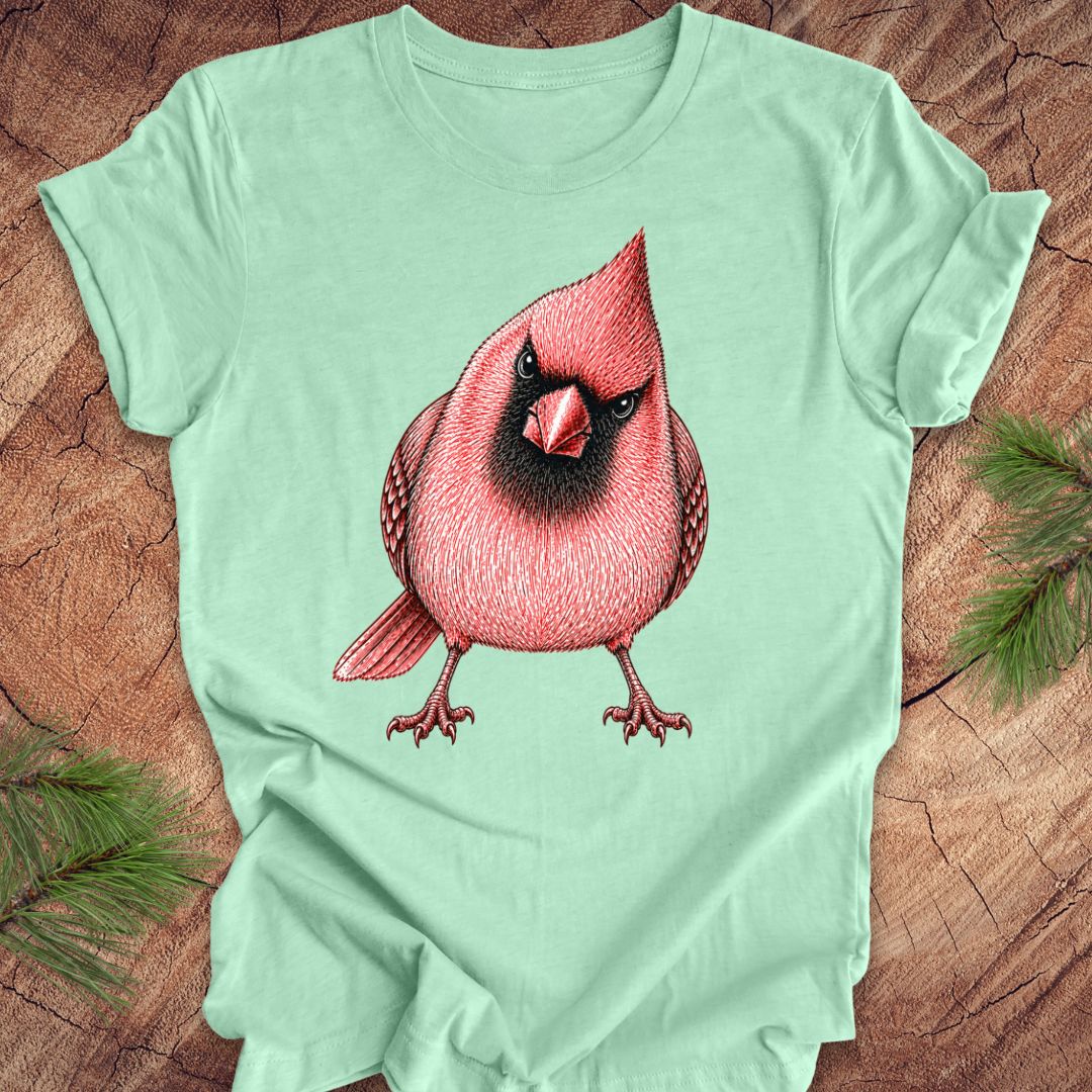 Light green t-shirt with a red cardinal bird design on a wooden surface.