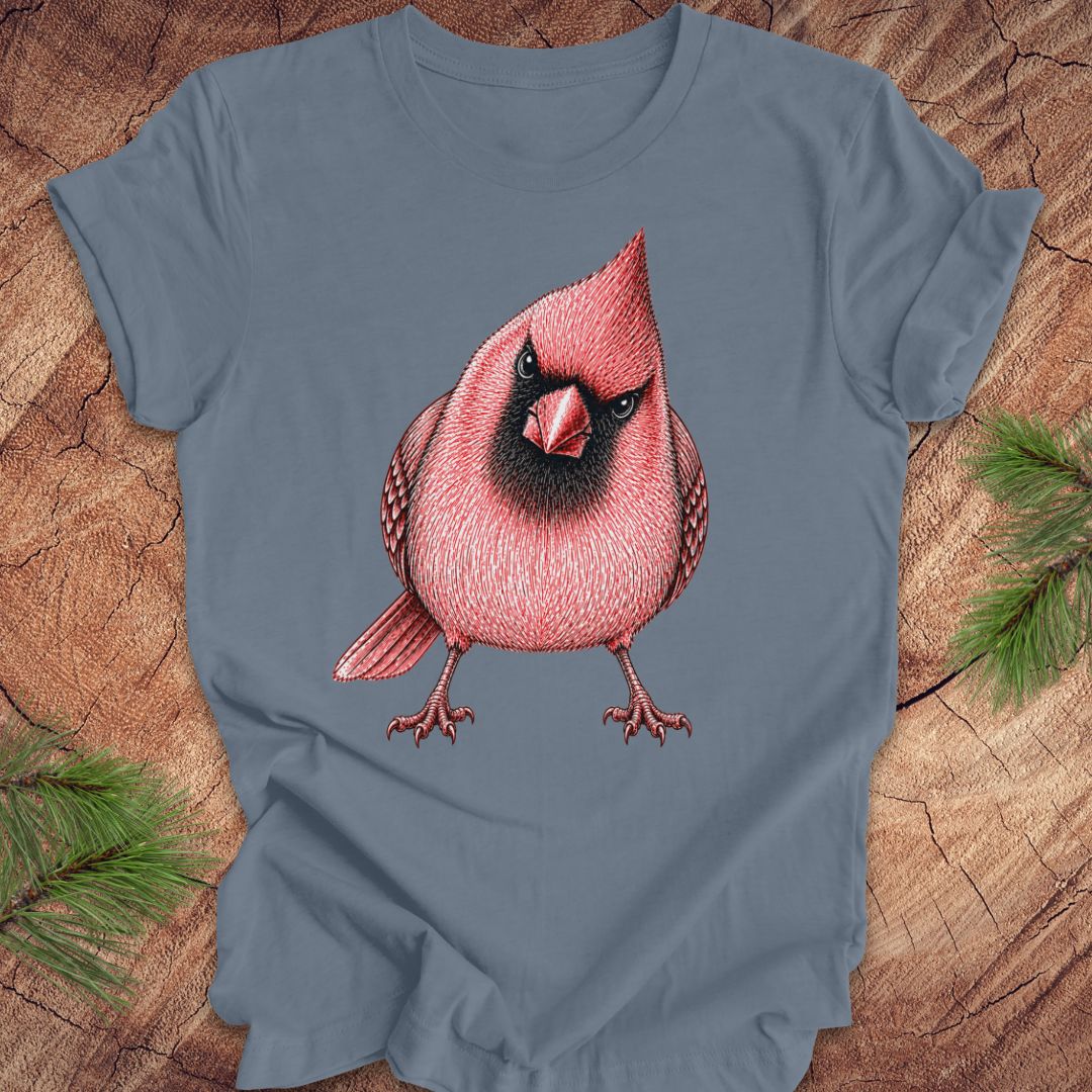 Blue t-shirt with a red cardinal bird design on a wooden surface with pine branches.