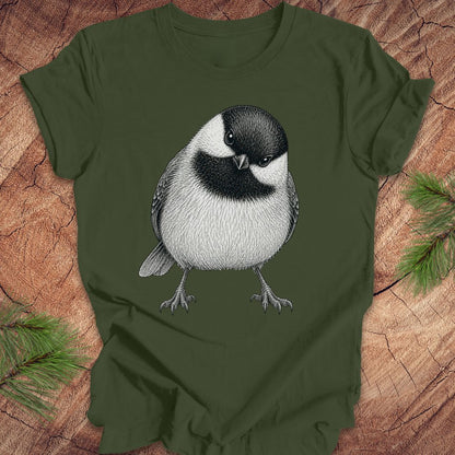 Green t-shirt with a chickadee design on a wooden surface