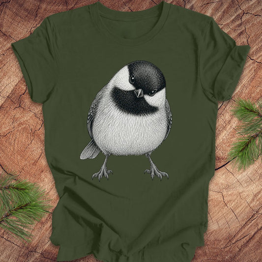 Green t-shirt with a chickadee design on a wooden surface