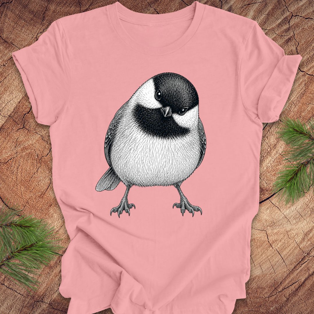Pink t-shirt with a chickadee design on a wooden surface