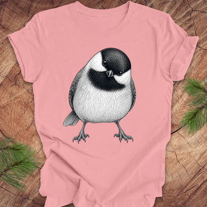 Pink t-shirt with a chickadee design on a wooden surface