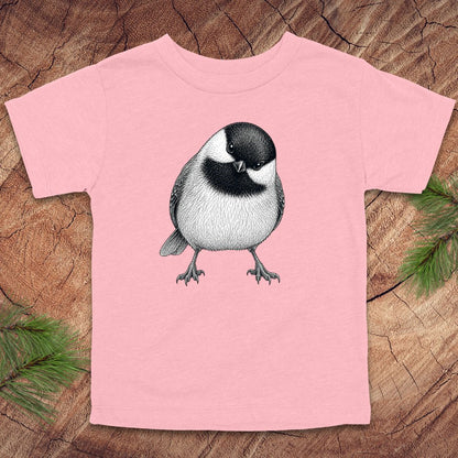 Pink toddler t-shirt with a chickadee design on a wooden surface