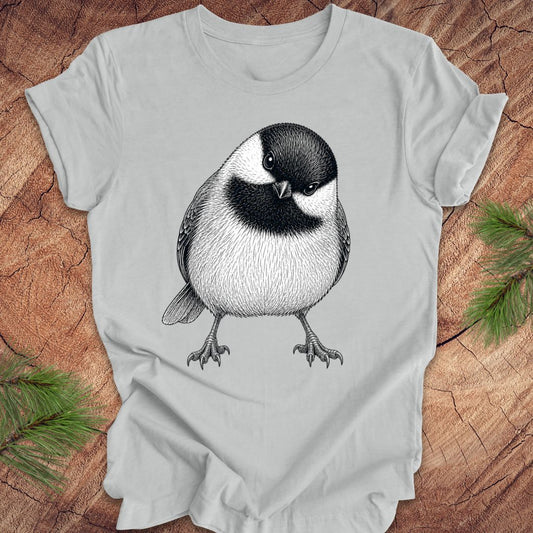 Grey t-shirt with a chickadee design on a wooden surface