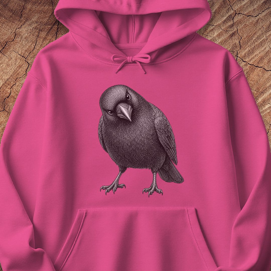 Heliconia pink hoodie with a detailed pencil-style American Crow tilting its head and glaring, laid flat on a rustic wood background.