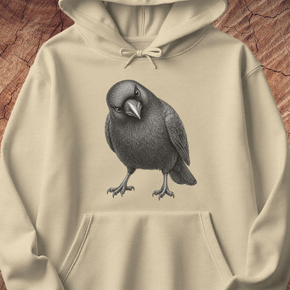 Sand beige hoodie with a detailed pencil-style American Crow tilting its head and glaring, laid flat on a rustic wood background.