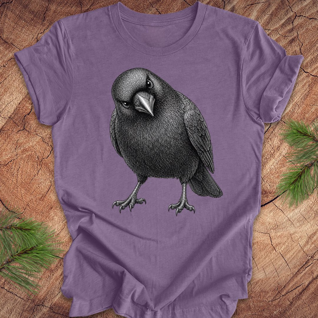 Purple t-shirt with a crow design on a wood background.