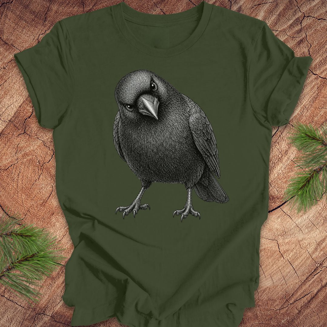 Green t-shirt with a crow design on a wood background.