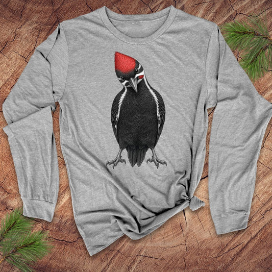 Gray long-sleeve shirt with a woodpecker design on a wooden surface with pine branches.