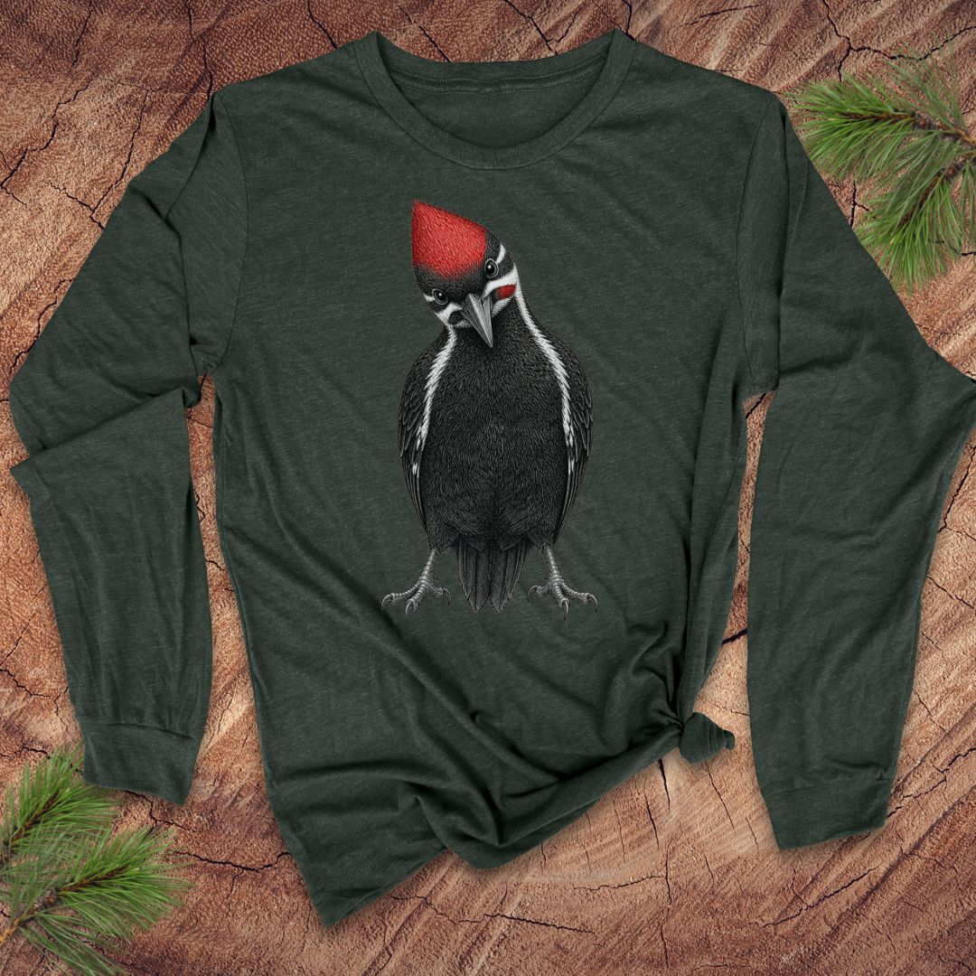 Green long-sleeve shirt with a woodpecker design on a wooden surface with pine branches.