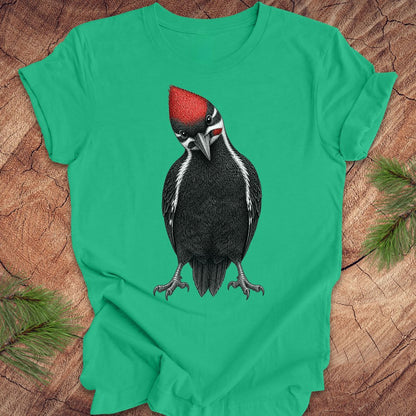 Green t-shirt with a woodpecker design on a wooden surface