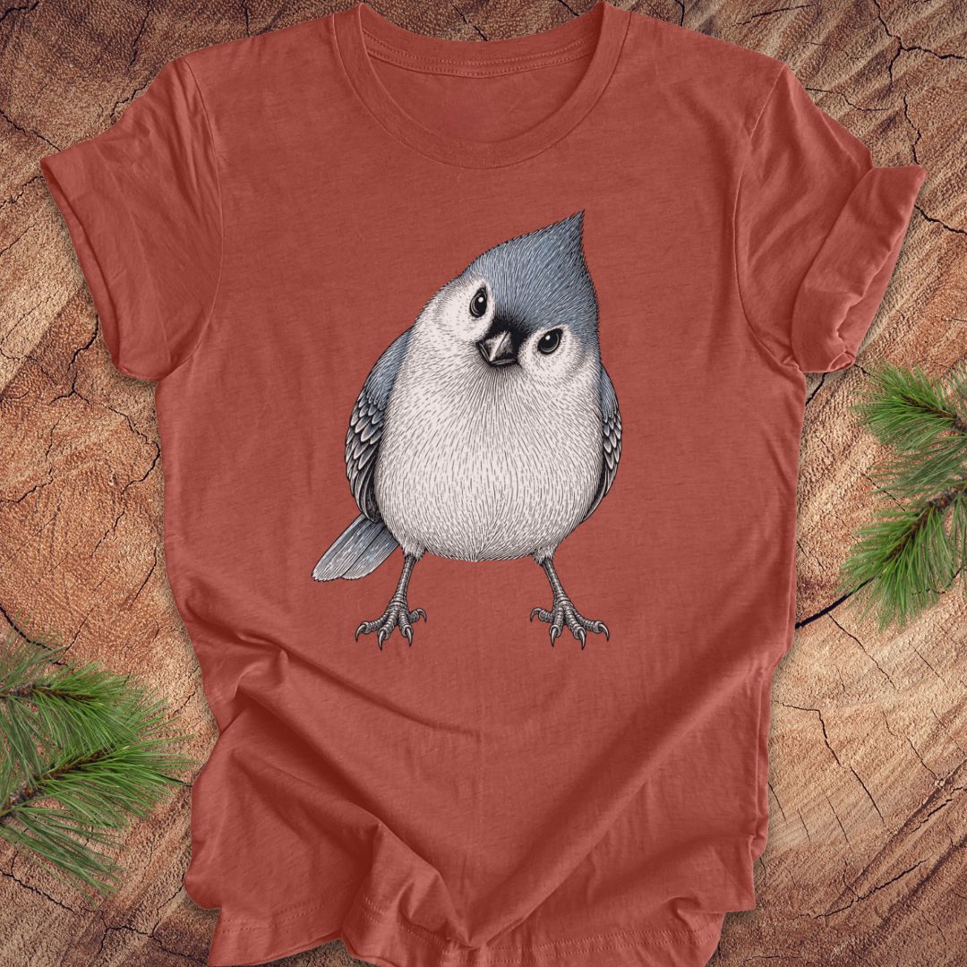 Red t-shirt with a titmouse graphic on a wooden surface