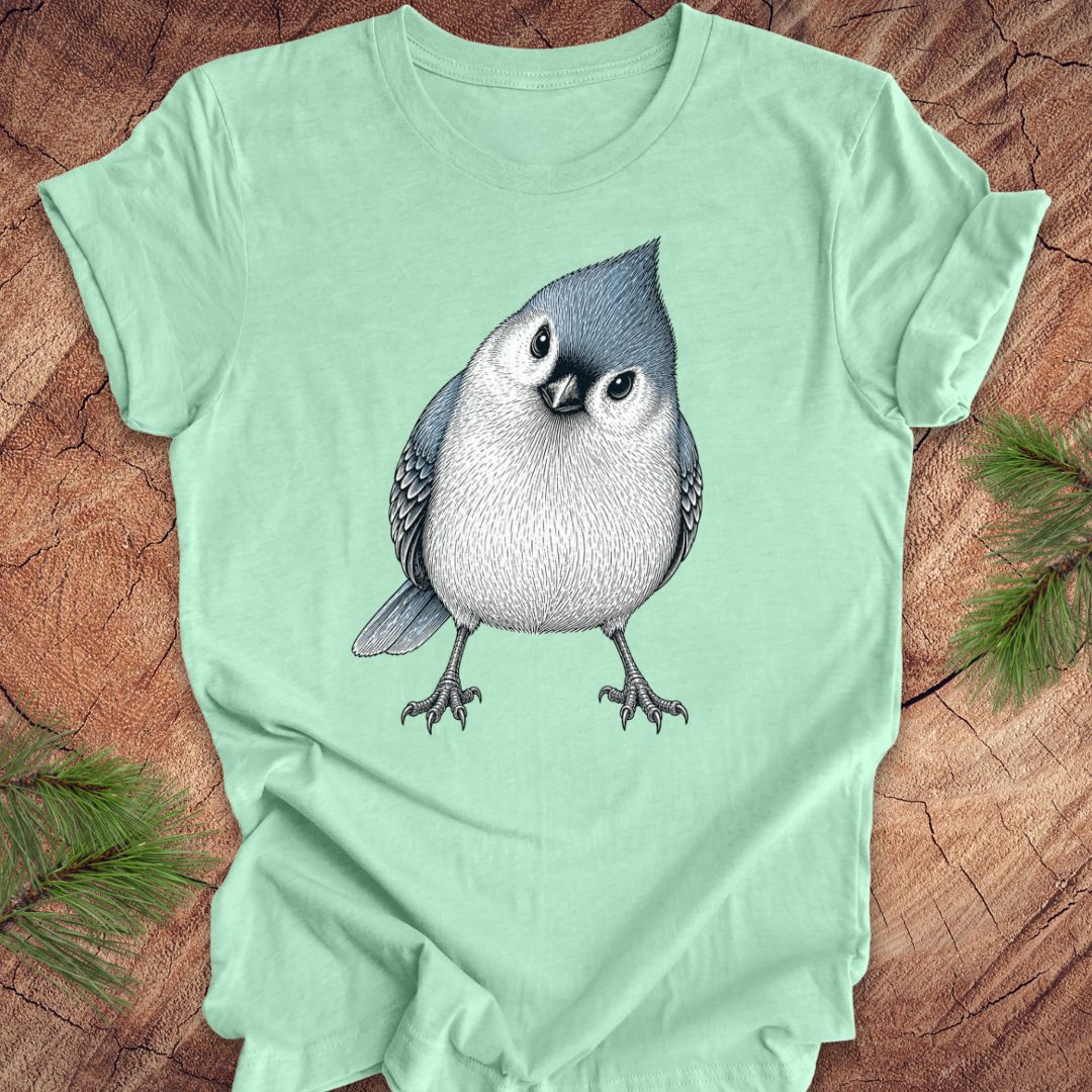 Mint green t-shirt with a titmouse graphic on a wooden surface