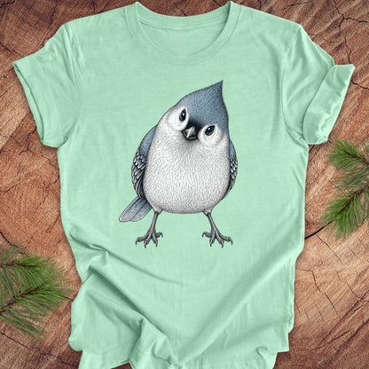 Mint green t-shirt with a titmouse graphic on a wooden surface