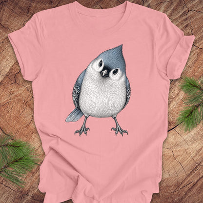 Pink t-shirt with a titmouse graphic on a wooden surface