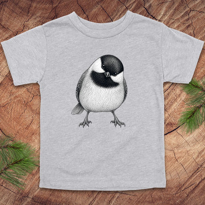 Gray toddler t-shirt with a chickadee design on a wooden surface