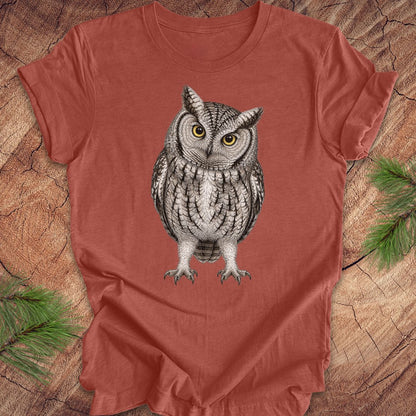 Red t-shirt with an owl design on a wooden surface