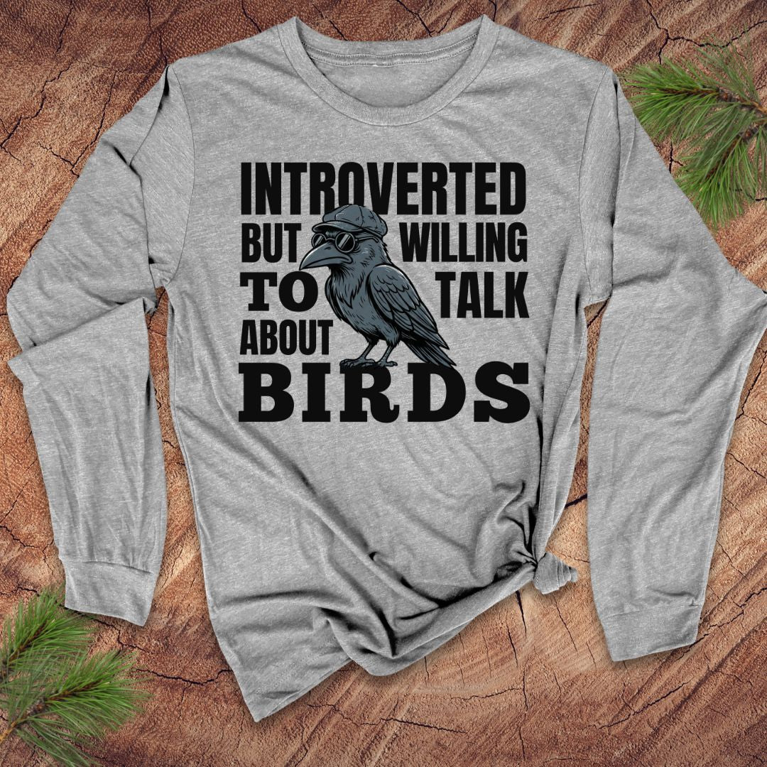 Gray long-sleeve shirt with a graphic of a bird and text on a wooden surface.