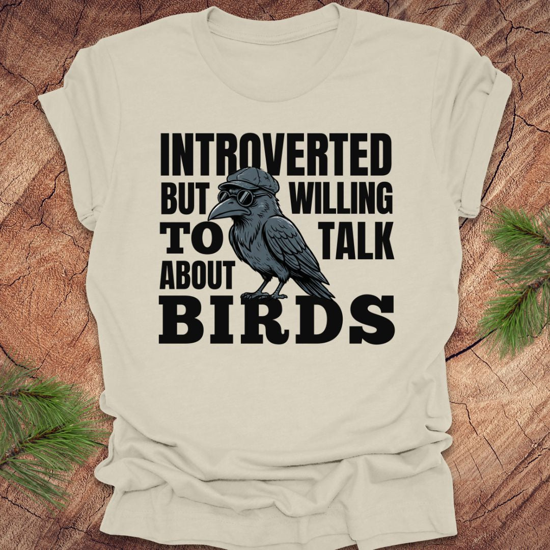 Beige t-shirt with a crow graphic and text on a wooden surface