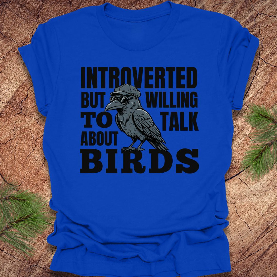 Royal blue t-shirt with a crow graphic and text on a wooden surface