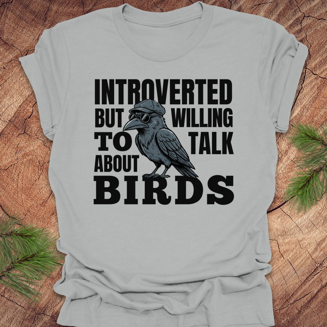 Gray t-shirt with a crow graphic and text on a wooden surface
