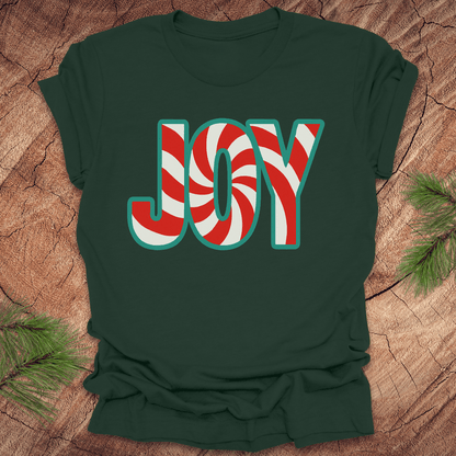 Forest green t-shirt with the text, "JOY" in a red and white pattern on a wood background