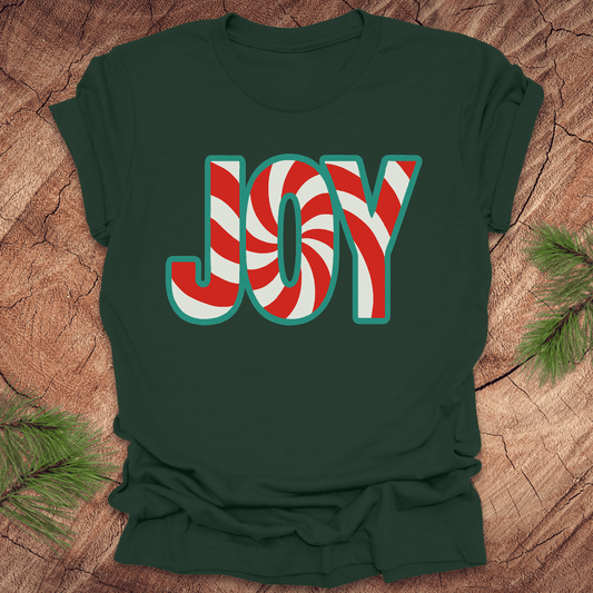 Forest green t-shirt with the text, "JOY" in a red and white pattern on a wood background