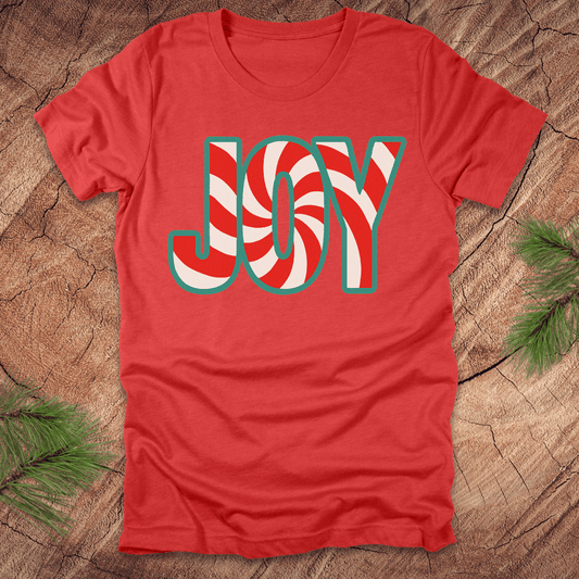Red t-shirt with the text, "JOY" in a red and white pattern on a wood background