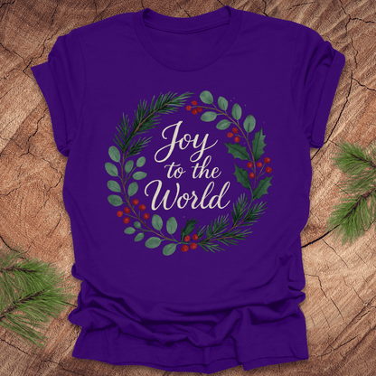 Purple t-shirt with wreath and text, 'Joy to the World' design on a wooden surface