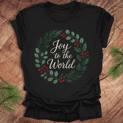 Black t-shirt with wreath and text, 'Joy to the World' design on a wooden surface