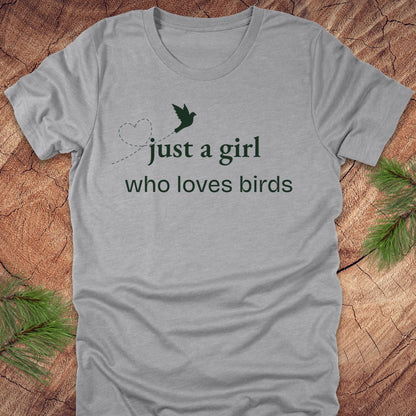 Gray t-shirt with 'just a girl who loves birds' text and a bird graphic on a wooden surface.