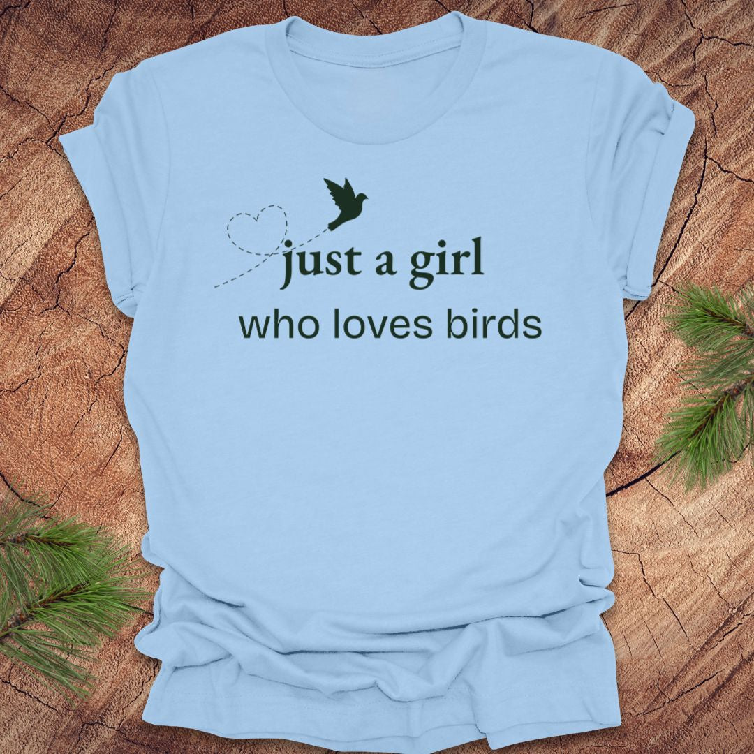 Light blue t-shirt with 'just a girl who loves birds' text on a wooden surface.