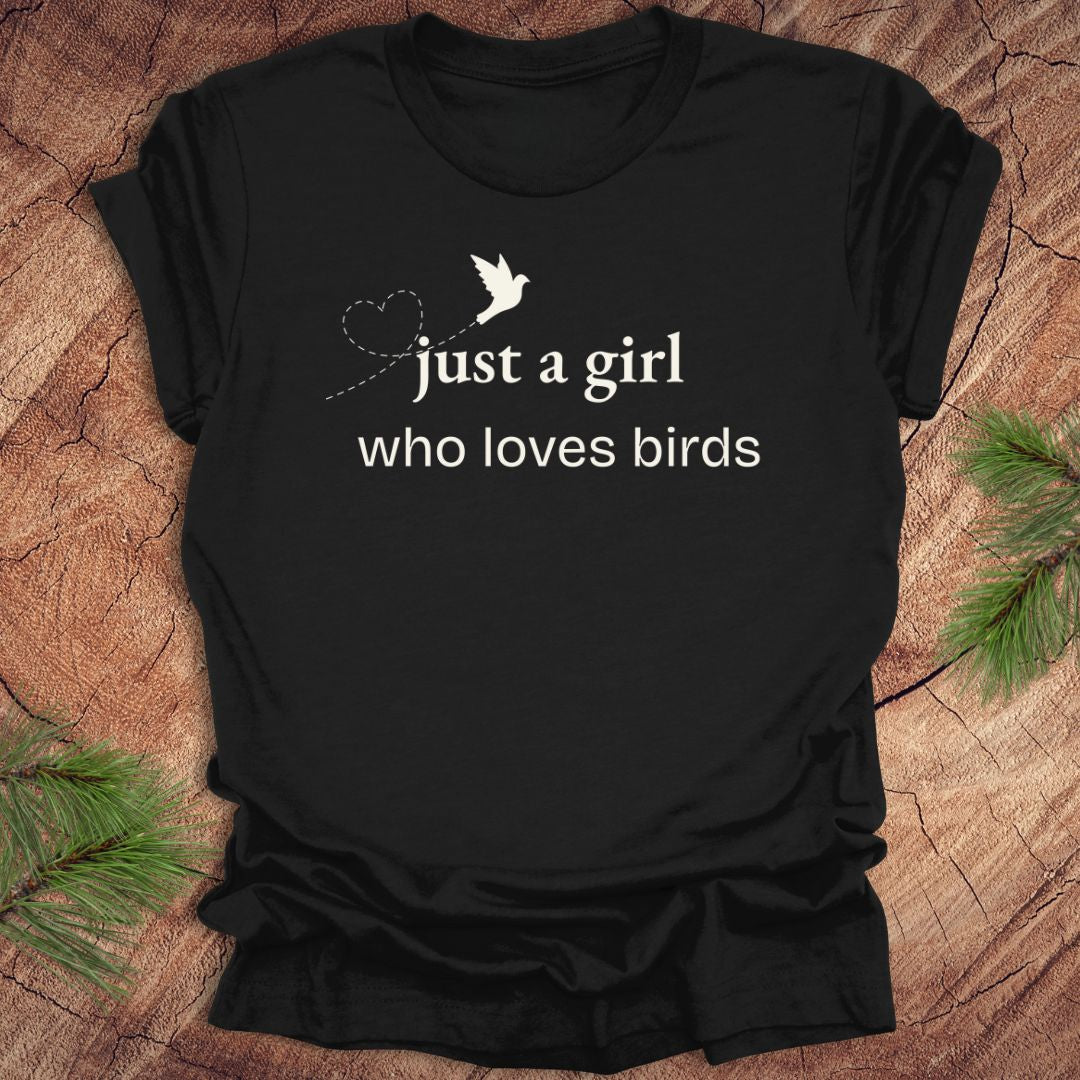Black t-shirt with 'just a girl who loves birds' text and bird graphic on a wooden surface.