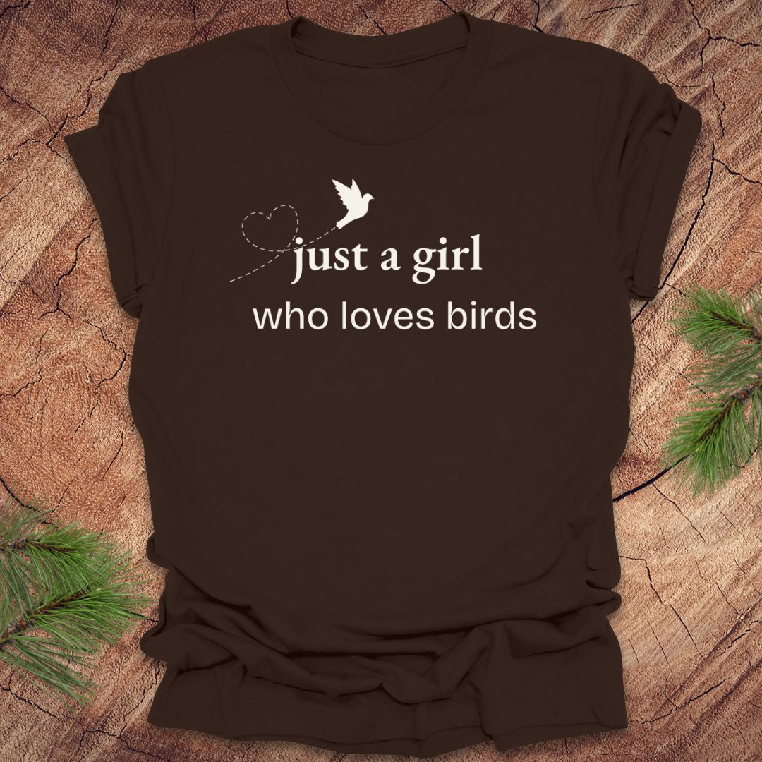 Brown t-shirt with 'just a girl who loves birds' text and bird graphic on a wooden surface.